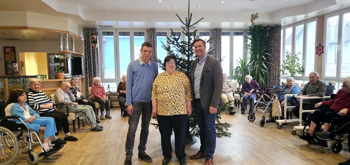 Foto (Stefanie Starke): MdL Josef Heisl (r.) hat den Bewohnerinnen und Bewohnern im Azurit Pflegezentrum in Hutthurm einen Christbaum vorbeigebracht  hier mit Bewohnerin Erika Schwarz und Hausleiter Johann Grimm.